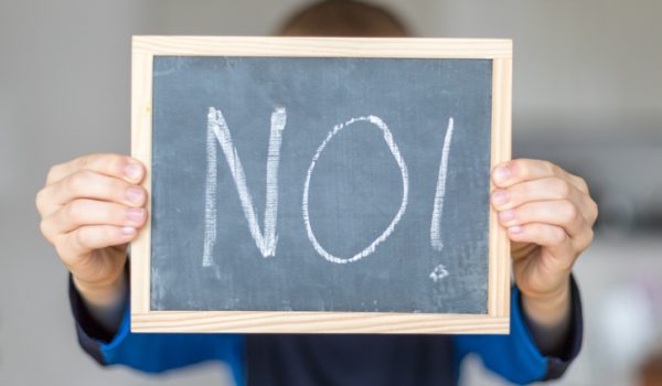 boy holds blackboard with NO letters