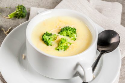 Broccoli, cheese and chicken soup, on gray stone table, copy space