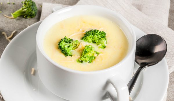 Broccoli, cheese and chicken soup, on gray stone table, copy space