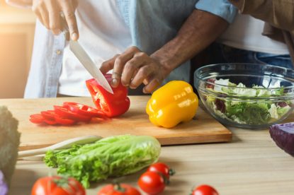 Black man cutting vegetables for healthy vegetarian salad in kitchen, closeup
